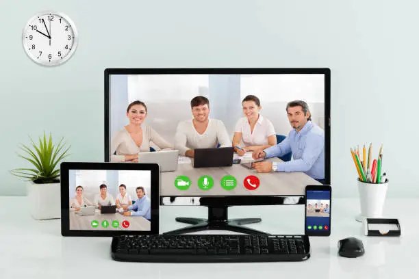 Computer Desktop With Digital Tablet And Mobilephone Showing Videoconferencing Application On Office Desk