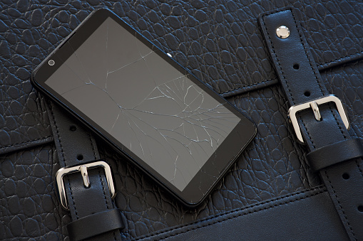 Broken glass of smart phone on the black leather bag