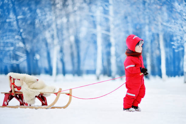 istock Little boy in red winter clothes with toboggan 842334164