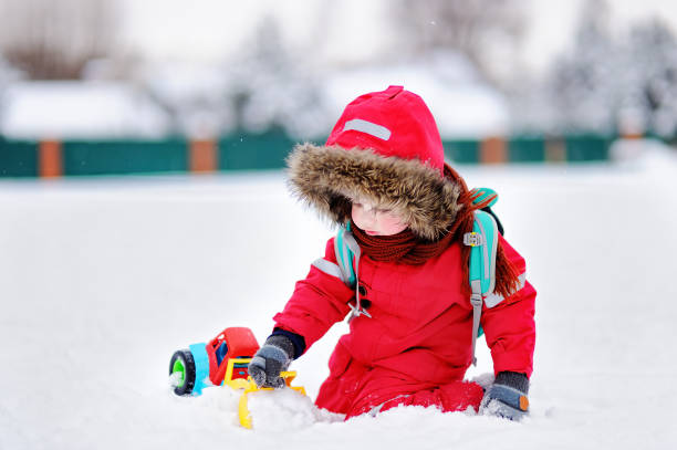 istock Little boy playing with bright car toy and fresh snow 842337124