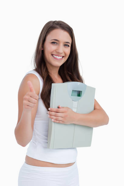 istock Smiling brunette putting her thumbs up while holding weighing scales 842340376