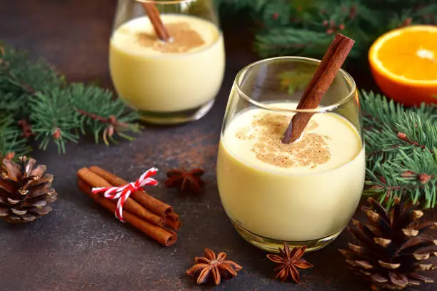 Winter spicy hot drink eggnog in a glasses on a dark slate,stone or concrete background.
