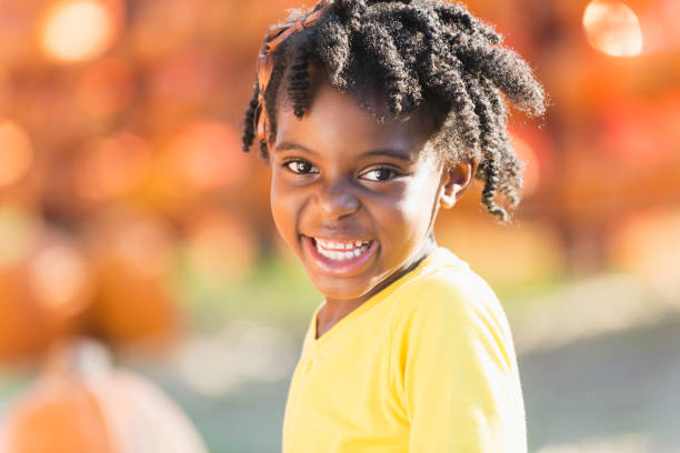 piccola ragazza afroamericana in una macchia di zucca - pumpkin child little girls pumpkin patch foto e immagini stock
