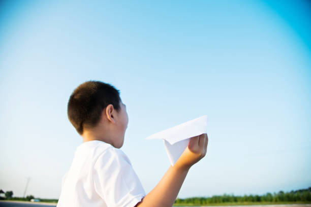 istock Boy hand holding a paper plane with the view of sky 842376302