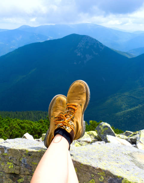 istock Female legs shod in outdoors boots. Mountain top relax. 842376524