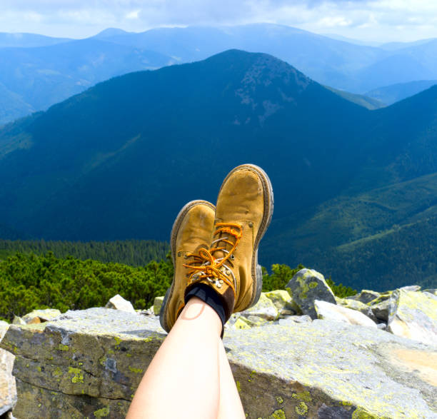 istock Female legs shod in outdoors boots. Mountain top relax. 842376538