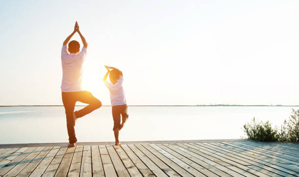 istock Father with his son doing yoga by the lake 842379144