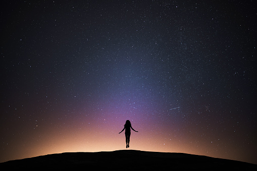 Woman fkying with night sky.