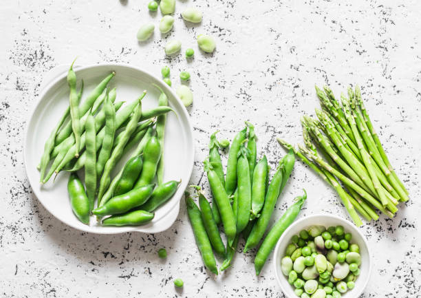 Green vegetables - asparagus, green beans and peas on a light background, top view