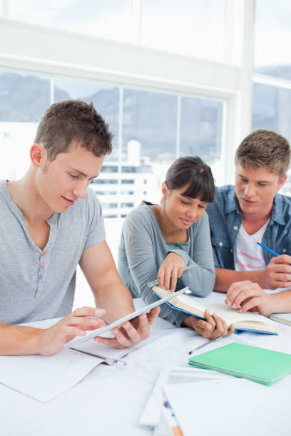 istock A group of students sit together using a tablet and a book to study 842388918