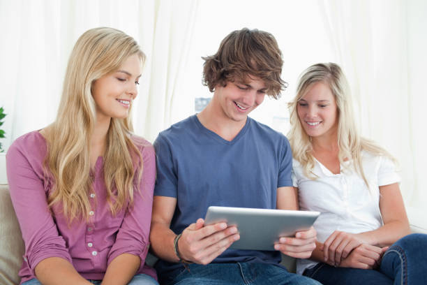 trzej przyjaciele siedzą razem, gdy patrzą na tablet - digital tablet young men women short hair zdjęcia i obrazy z banku zdjęć
