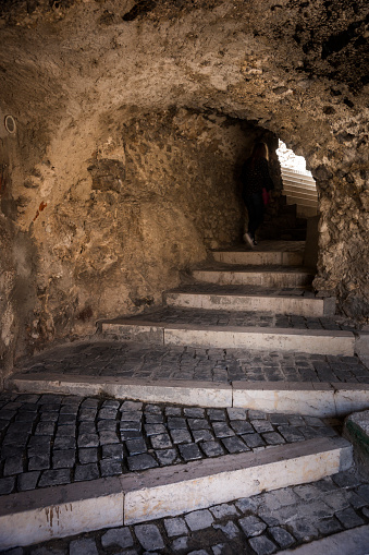 Shadowy figure climbs cobblestone steps through a mysterious sporti, one of nine limestone rock tunnels in the fortified medieval village of Castel del Monte in Gran Sasso National Park, L'Aquila province, Abruzzo, Italy, Europe