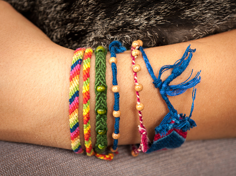 Closeup of a colorful friendship bracelet on a child's hand holding a cat
