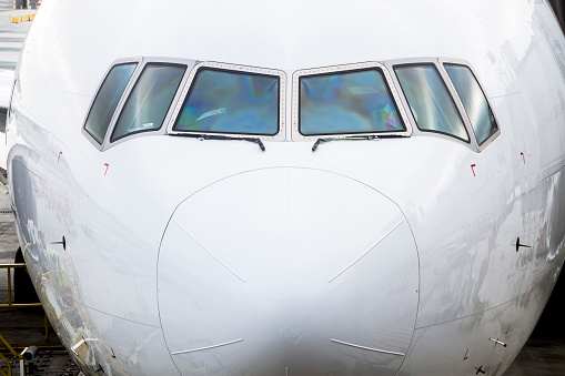 Extreme close-up of front nose and cockpit of modern long-range wide-body jetliner. ID and logos removed.