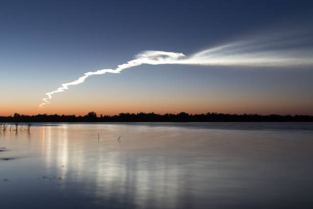istock Smoke trail from a rocket at sunset with reflection in water 842442414
