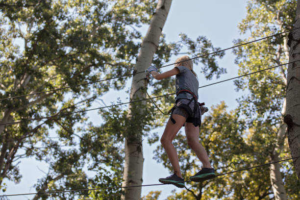 istock Woman enjoying in a climbing adventure high wire park between trees. Challenge, accomplishment, success, breaking fear concept. 842442558