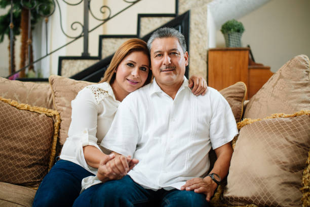 istock Hispanic mature couple sitting on sofa and smiling 842443852