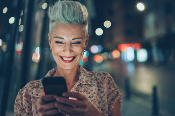 Woman laughing at a message outdoors at night