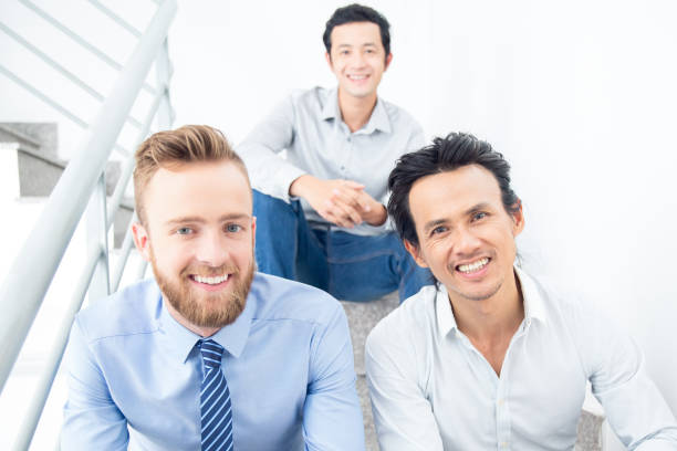 istock Three Smiling Business Men Sitting on Stairs 842447110