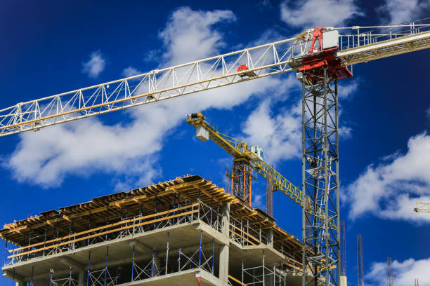 istock Construction concept. A new building under construction against the sky. Blue background. New urban city. Machinery, cranes and builders on scaffolding. Heavy industry and safety at work 842447878