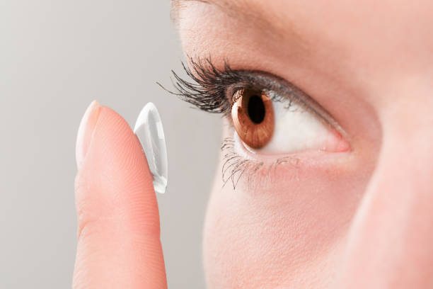 mujer inserción de una lente de contacto en los ojos. - human eye eyesight optometrist lens fotografías e imágenes de stock