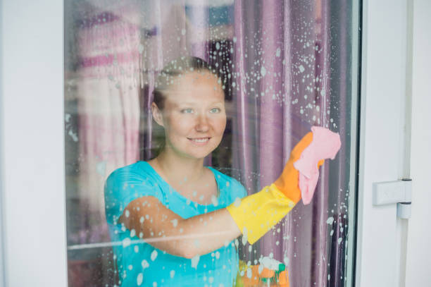 istock Beautiful female maid doing the housework while using a spray, washing windows 842451262