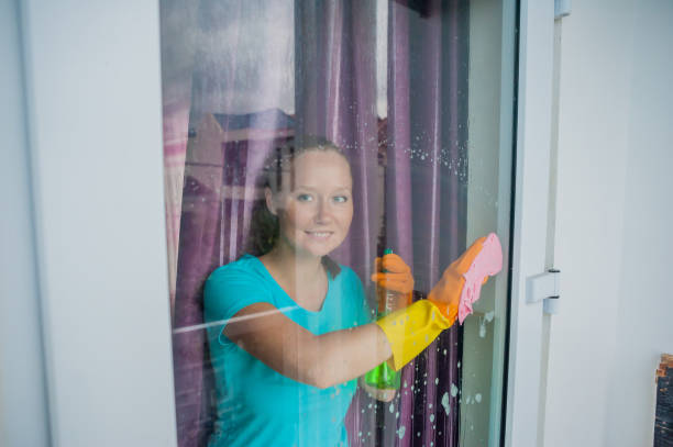 istock Beautiful female maid doing the housework while using a spray, washing windows 842451320