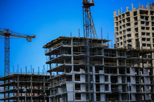 istock Construction concept. A new building under construction against the sky. Blue background. New urban city. Machinery, cranes and builders on scaffolding. Heavy industry and safety at work 842451418