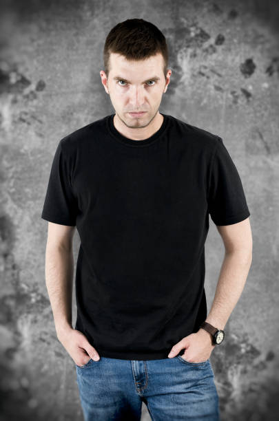 istock Angry man in black t-shirt on grunge background 842452786