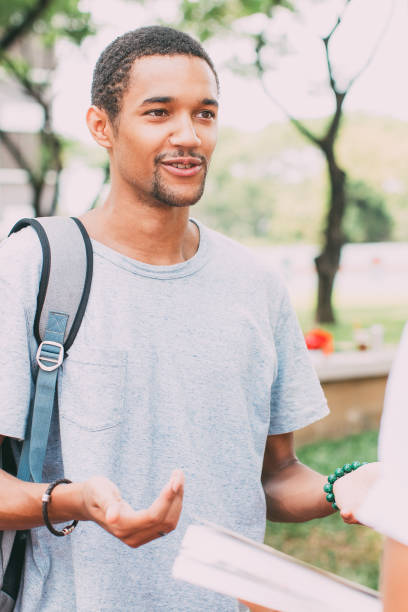 istock Smiling young student man taking to friend outdoor 842454704