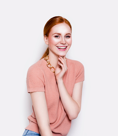 Young beautiful redhead woman wearing stylish clothes pink color top and black leather shorts Fashion model studio portrait on white background