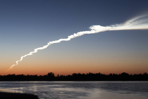 istock Smoke trail from a rocket at sunset with reflection in water 842460768