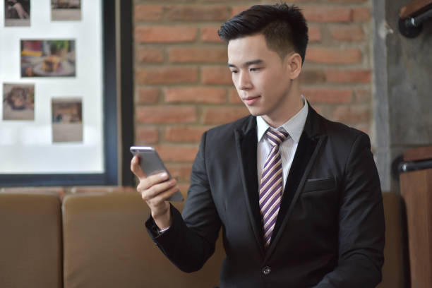 istock Happy  businessman using cellphone while sitting on sofa at his modern home.Concept of young people working on mobile devices.Blurred background 842462112