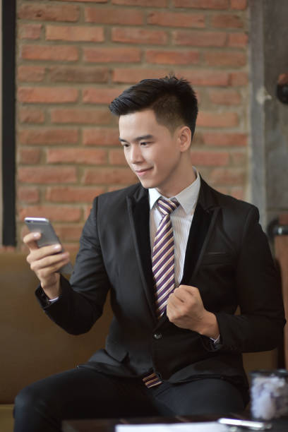 istock Happy  businessman using cellphone while sitting on sofa at his modern home.Concept of young people working on mobile devices.Blurred background 842462116