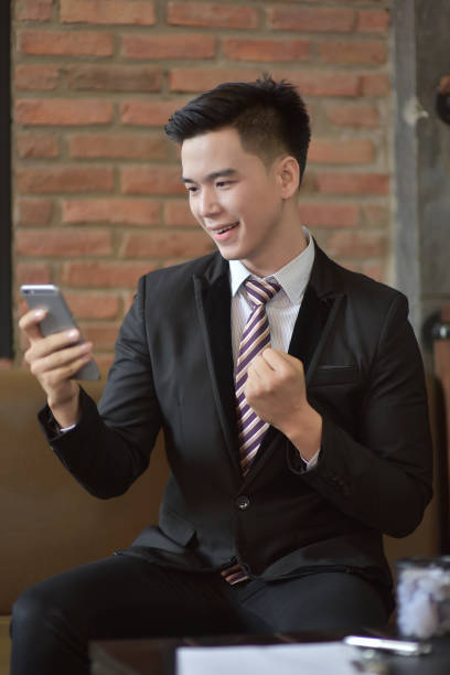istock Happy  businessman using cellphone while sitting on sofa at his modern home.Concept of young people working on mobile devices.Blurred background 842462118