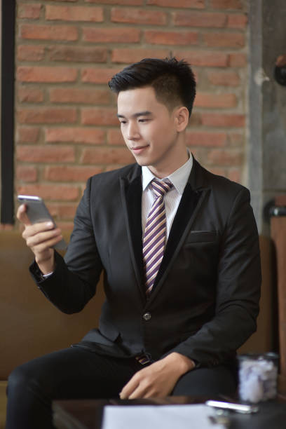 istock Happy  businessman using cellphone while sitting on sofa at his modern home.Concept of young people working on mobile devices.Blurred background 842462120