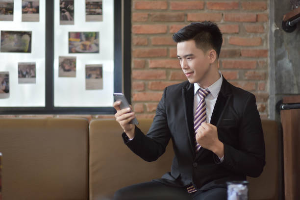 istock Happy  businessman using cellphone while sitting on sofa at his modern home.Concept of young people working on mobile devices.Blurred background 842462124