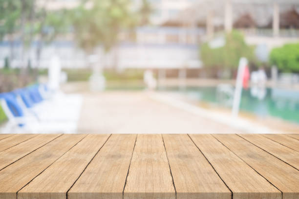 istock Empty wooden table in front with blurred background of swimming pool 842465118