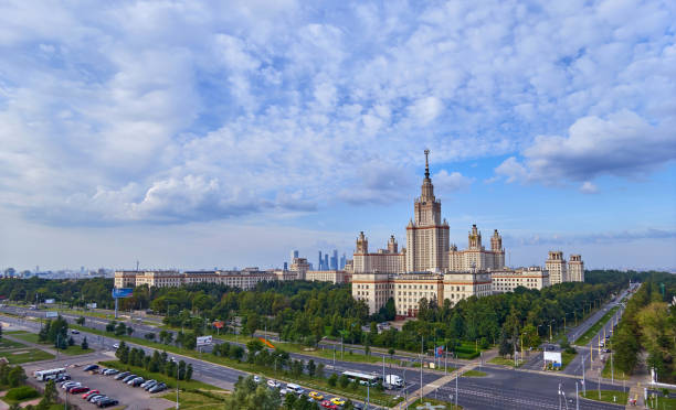 istock Wide angle panoramic landscape view of dramatic clouds over the sunny summer campus of Lomonosov Moscow State University under blue sky 842469292