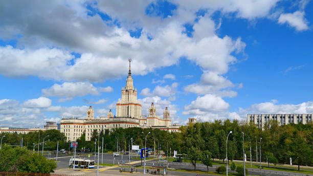 istock Wide angle panoramic landscape view of dramatic clouds over the sunny summer campus of Lomonosov Moscow State University under blue sky 842469354