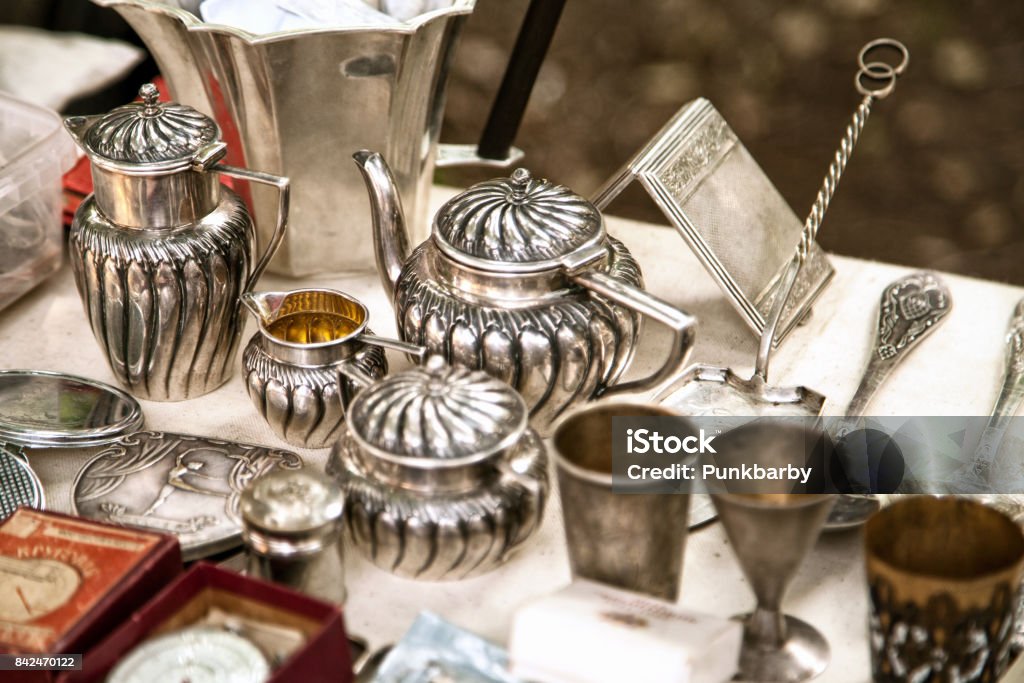 Antique silver teapots, creamer and other utensils at a flea market Old metal tableware collectibles at a garage sale. Antique Stock Photo