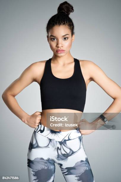 Strong Young Woman In Sports Wear Studio Shot Stock Photo - Download Image Now - Gray Background, Leggings, Sports Bra