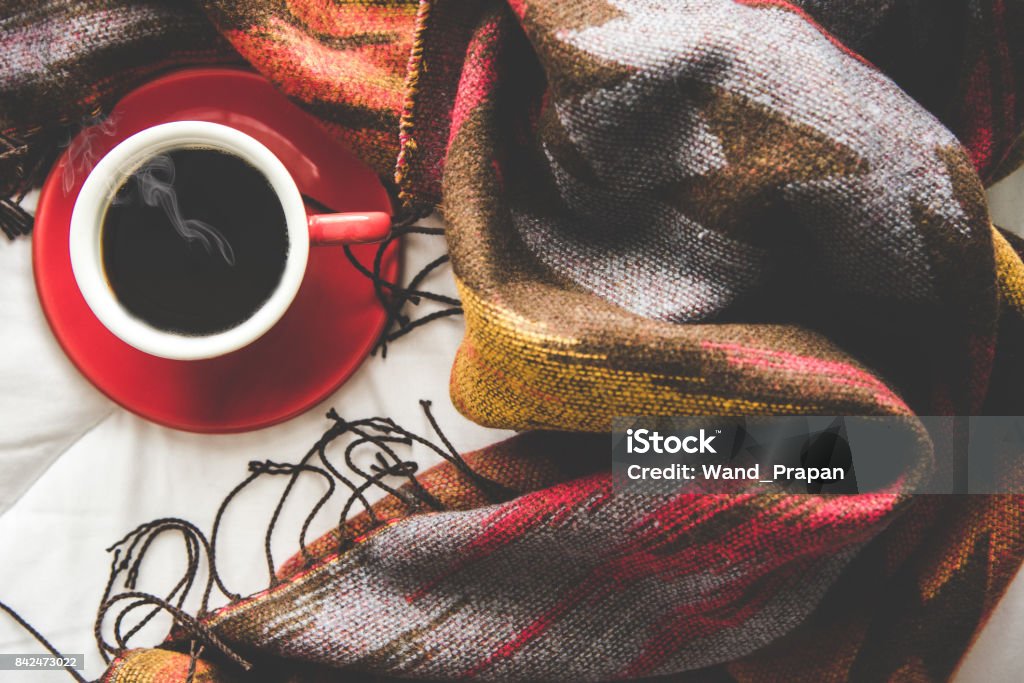 Cozy winter home background, cup of hot coffee with marshmallow, warm knitted sweater on white bed background, vintage tone.  Lifestyle concept Winter Stock Photo