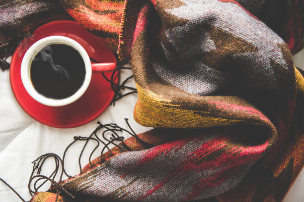 Cozy winter home background, cup of hot coffee with marshmallow, warm knitted sweater on white bed background, vintage tone.  Lifestyle concept Cozy winter home background, cup of hot coffee with marshmallow, warm knitted sweater on white bed background, vintage tone.  Lifestyle concept winter still life stock pictures, royalty-free photos & images