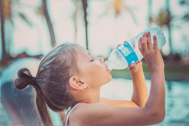 un niño está bebiendo agua de una botella. caluroso día de verano. - sediento fotografías e imágenes de stock