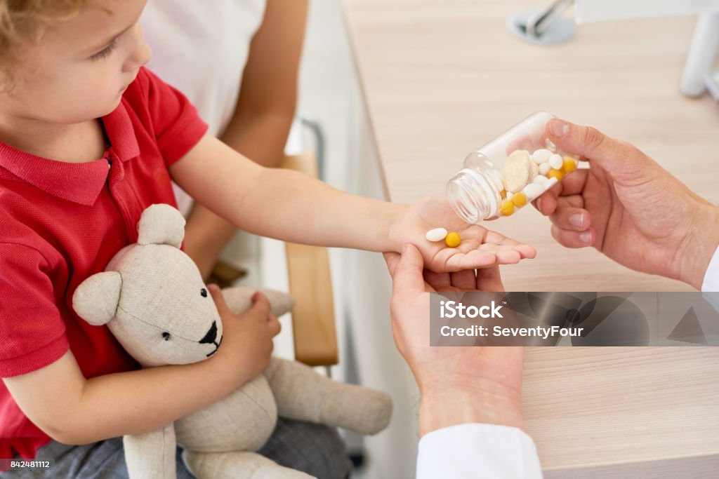 Vitamin C for Children Closeup of unrecognizable doctor giving vitamins to curly little boy during appointment Child Stock Photo