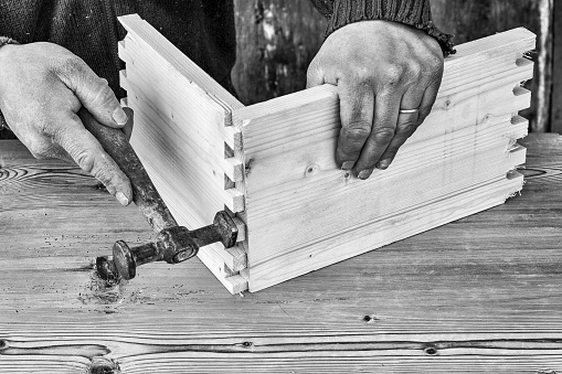 carpenter builds a wooden drawer with a hammer and joints