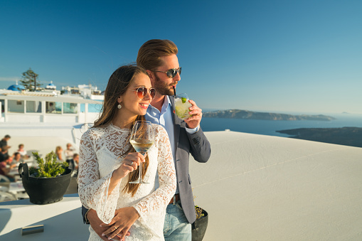 sunset in greece - young couple in evening dress enjoying their drinks greek island of santorini