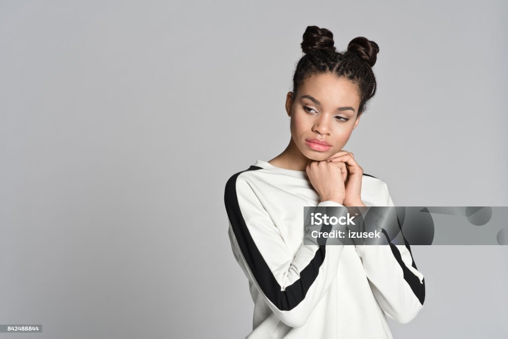 Pensive afro american cute teenager woman Studio portrait of pensive afro american cute teenage woman. Studio shot, grey background. Hair Bun Stock Photo