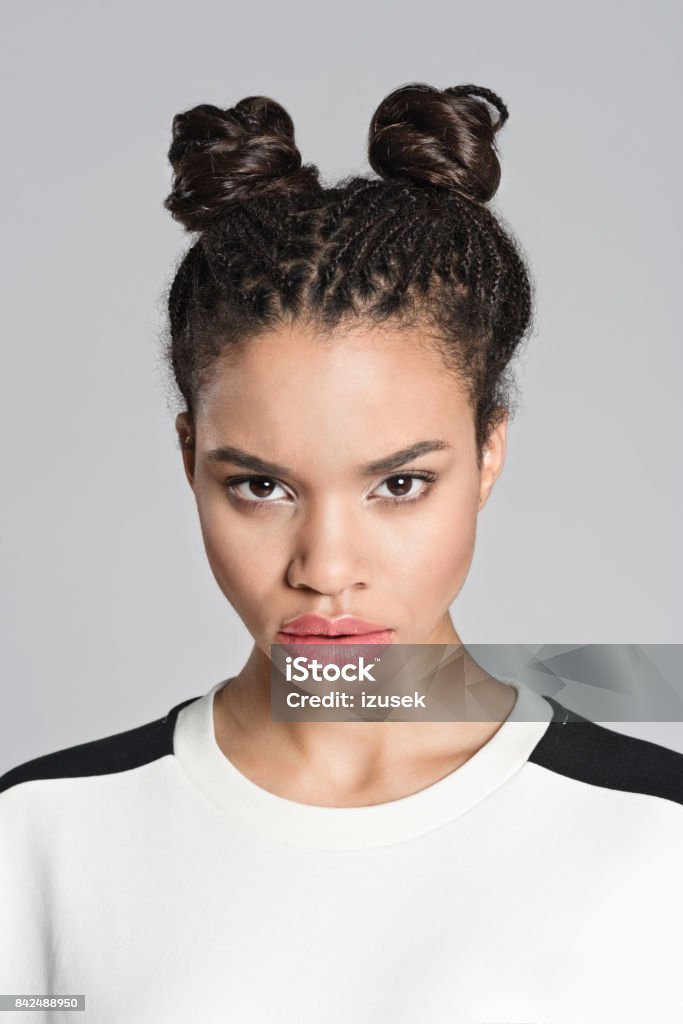 Displeased afro american teenager girl Studio portrait of angry afro american teenage woman looking at camera. Studio shot, grey background. 16-17 Years Stock Photo
